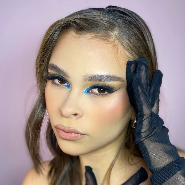 Maquillaje con delineado gráfico azul y guantes de tul negro.